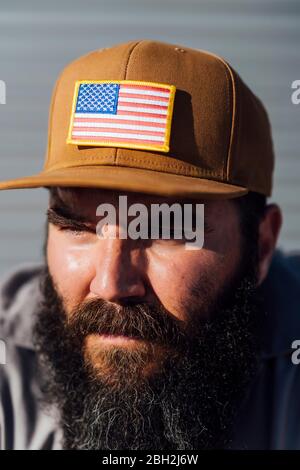 Porträt eines bärtigen Mannes mit Baseballmütze und amerikanischer Flagge Stockfoto