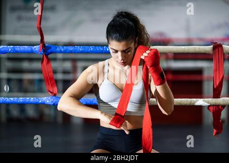 Junge Frau, die im Boxclub einen Verband um die Hand bindet Stockfoto