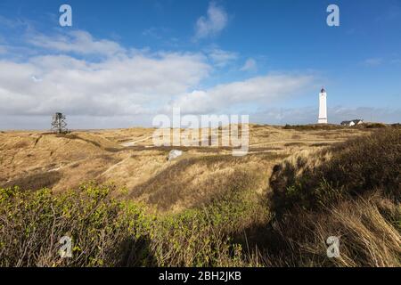 Dänemark, Romo, Blavand, Wolken über grasbewachsenen Küstenlandschaft mit Leuchtturm im Hintergrund Stockfoto