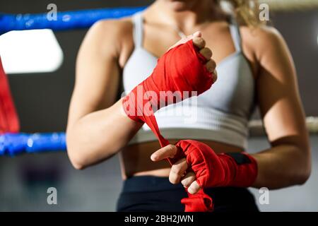 Nahaufnahme einer jungen Frau, die im Boxclub einen Verband um ihre Hand bindet Stockfoto