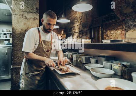 Der Koch arrangiert das Essen auf dem Teller, bevor er im Restaurant serviert Stockfoto