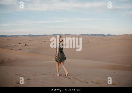 Rückansicht einer blonden Frau, die auf Sanddüne, Algodones Dunes, Brawley, USA, läuft Stockfoto