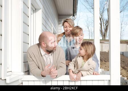 Glückliche Familie auf der Veranda ihres Hauses reden Stockfoto