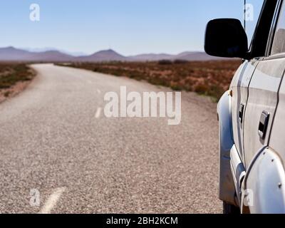 Marokko, Nahaufnahme von 4x4 Auto fahren entlang leerer Asphaltstraße Stockfoto