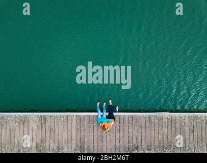 Zwei glückliche Freunde sitzen zusammen auf dem Steg umarmt einander, Valdemurio Reservoir, Asturien, Spanien Stockfoto