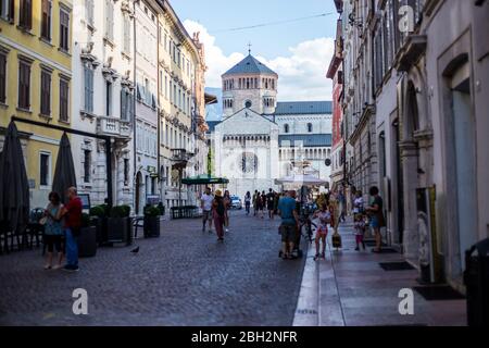 Trento, Italien - 15. August 2019: Menschen, die in der Altstadt von Trento spazieren gehen, mit der St. Vigil Kathedrale im Hintergrund Stockfoto