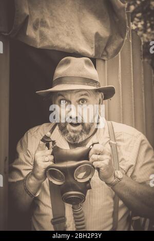 Vintage Sepia-Porträt, 1940er Mann mit Gasmaske isoliert im Freien bei Anderson Tierheim, Black Country Museum 1940er WWII Kriegszeit Sommer Veranstaltung, Großbritannien. Stockfoto