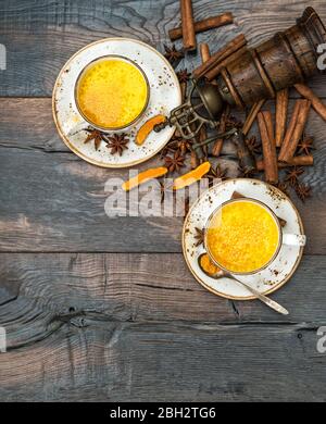 Goldene Milch. Heißer Kurkuma-Drink mit Gewürzen auf rustikalem Holzhintergrund Stockfoto