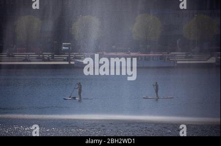 Hamburg, Deutschland. April 2020. Stand-up-Paddler sind bei strahlendem Sonnenschein auf der Binnenalster hinter der Alster vor dem Jungfernstieg unterwegs. Kredit: Christian Charisius/dpa/Alamy Live News Stockfoto