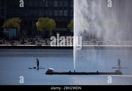 Hamburg, Deutschland. April 2020. Stand-up-Paddler sind bei strahlendem Sonnenschein auf der Binnenalster hinter der Alster vor dem Jungfernstieg unterwegs. Kredit: Christian Charisius/dpa/Alamy Live News Stockfoto