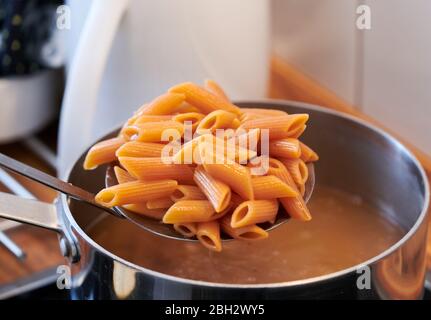 Italienische Pasta glutenfrei und vegan, mit Linsenmehl, während es aus dem Topf in der Küche abgelassen wird Stockfoto