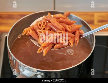 Italienische Pasta glutenfrei und vegan, mit Linsenmehl, während es aus dem Topf in der Küche abgelassen wird Stockfoto