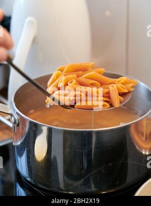 Italienische Pasta glutenfrei und vegan, mit Linsenmehl, während es aus dem Topf in der Küche abgelassen wird Stockfoto