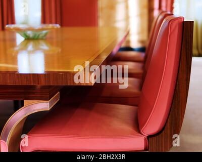 Wunderschöner alter Art Deco Holztisch und rote Stühle im Speisesaal, Eltham Palace, London, Großbritannien. Stockfoto