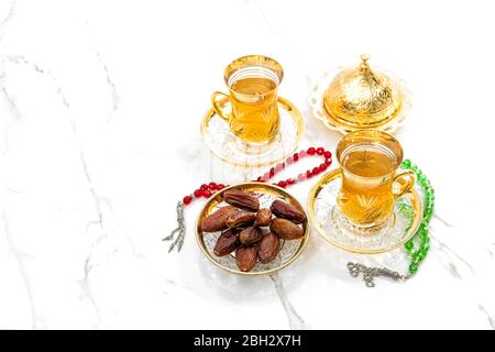 Teebecher mit Datteln und Rosenkranz auf weißem Hintergrund. Ramadan kareem Stockfoto