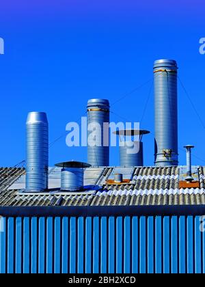 Satz von 3 großen Lüftungskanälen über dem Werksdach gegen den tiefblauen Himmel Stockfoto