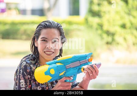 Asiatische Frau mit einer Wasserpistole spielen Songkran Festival oder Thai Neujahr in Thailand. Stockfoto