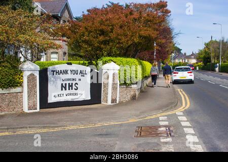 22. April 2010 Groomsport Road, Bangor, Nordirland. Ein Mann und eine Frau, die an einer handschriftlichen Botschaft der Unterstützung für den National Health Service vorbeigehen Stockfoto