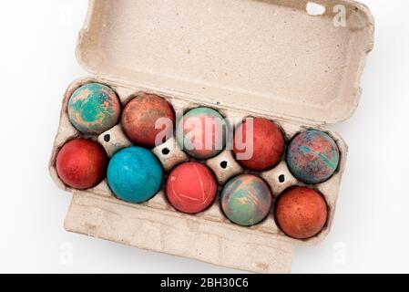 Bunte Ostereier in Karton Eierbox auf weißem Hintergrund. Rohe Hühnereier in offener Eierbox auf weißem Hintergrund. Eier in der Packung. Stockfoto