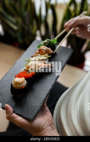 Verschiedene frische Sushi-Gunkan Maki mit Meeresfrüchten. Set von Gunkans in den Händen. Selektiver Fokus. Stockfoto