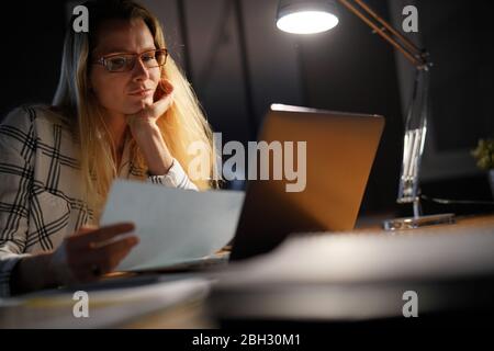 Junge Frau, die spät in der Nacht arbeitet Stockfoto