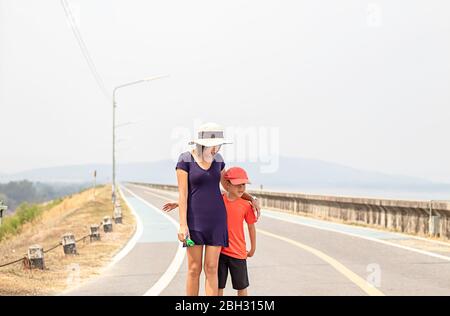 Porträt einer Mutter und Sohn zu Fuß auf der Straße Hintergrund Berge und Wasser bei Supanburi Krasiew Dam, Thailand. Stockfoto