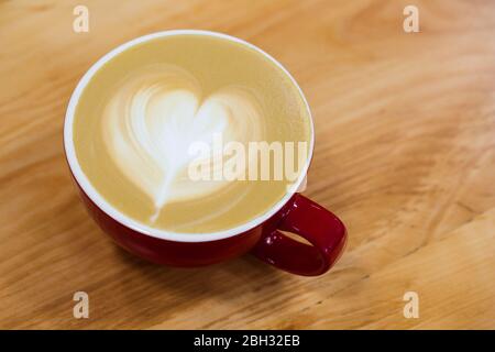 Eine Tasse heißer Kunst-Cappuccino mit einem Herz auf einem Schaumstoff. Stockfoto