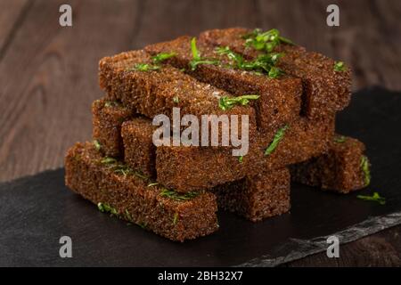 Gebratene Croutons mit Knoblauch auf einem schwarzen Brett. Biernack. Stockfoto