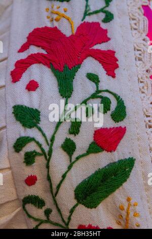 Nahaufnahme eines Maya-Kleides mit bestickten Blumen. Mexikanisches Pink ist traditionell in Kleidung und Wohnkultur. Stockfoto