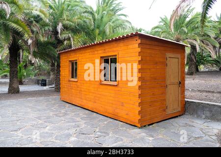 Kleine Holzkabine mit Fenstern, Dach aus Wellblech, von Palmen umgeben, Blick aus dem Winkel. Stockfoto