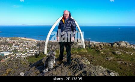 Mann und Hund an der Spitze von Berwick Law, North Berwick - Whalebones hinter und Firth of Forth Stockfoto