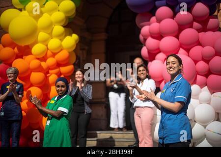 NHS-Krankenschwestern, Chirurgen, Ärzte und Hilfspersonal helfen, eine Regenbogenballonanzeige vor dem National Hospital for Neurology and Neurosurgery in Holborn, London, zu enthüllen, um der Öffentlichkeit für ihre Unterstützung während der laufenden Coronavirus-Pandemie zu danken. Stockfoto