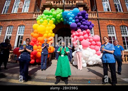 NHS-Krankenschwestern, Chirurgen, Ärzte und Hilfspersonal helfen, eine Regenbogenballonanzeige vor dem National Hospital for Neurology and Neurosurgery in Holborn, London, zu enthüllen, um der Öffentlichkeit für ihre Unterstützung während der laufenden Coronavirus-Pandemie zu danken. Stockfoto