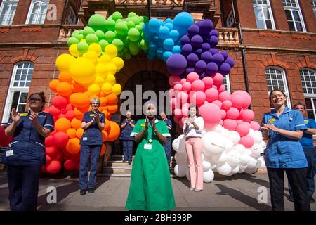 NHS-Krankenschwestern, Chirurgen, Ärzte und Hilfspersonal helfen, eine Regenbogenballonanzeige vor dem National Hospital for Neurology and Neurosurgery in Holborn, London, zu enthüllen, um der Öffentlichkeit für ihre Unterstützung während der laufenden Coronavirus-Pandemie zu danken. Stockfoto