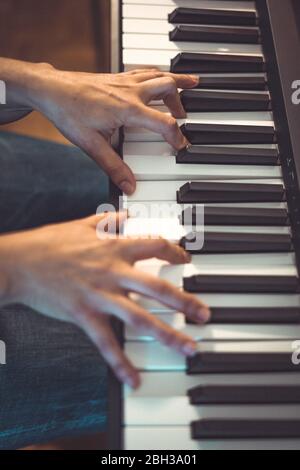 Hübsche Frau spielt zu Hause an beengten Tagen Klavier Stockfoto