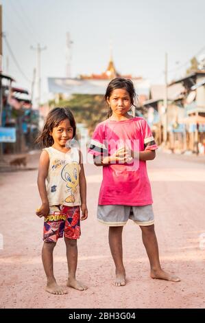 Zwei junge kambodschanische Mädchen machen eine Pause für ein Foto entlang der Hauptstraße im schwimmenden Dorf Kampong Phluk, nahe Tonle SAP See, Kambodscha. Stockfoto