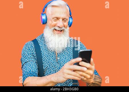 Senior Mann mit mobilen Smartphone während Musik-Playlist mit kabellosen Kopfhörern hören - Reife Hipster Mann mit Spaß mit Technologie im Freien Stockfoto