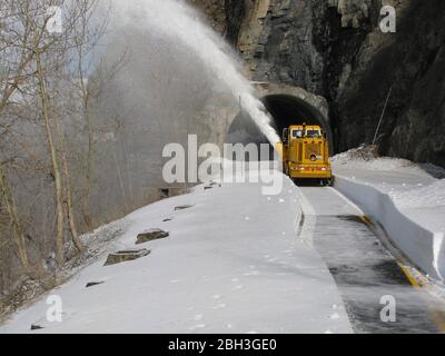 Schneeräumgeräte am West Side Tunnel entlang der gewundenen Straße zur Sonne auf einer Höhe von 6,646 Fuß im Glacier National Park 14. April 2020 in Glacier, Montana. Die Straßenräumung geht weiter, obwohl der Park wegen der COVID-19, einer Coronavirus-Pandemie, für Besucher gesperrt ist. Stockfoto