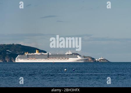 Costa Mediterranea Kreuzfahrtschiff, das an einem sonnigen Tag aus der Bucht von Dublin mit Howth Head und dem Bailey Leuchtturm im Hintergrund segelt. Stockfoto