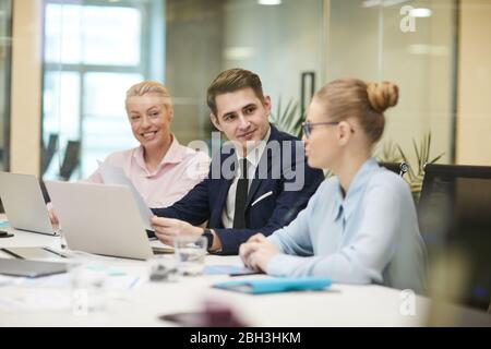 Gruppe von Geschäftsleuten, die während des Meetings im Büro am Tisch sitzen und gemeinsam den Geschäftsplan besprechen Stockfoto