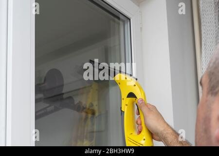 Ein Mann wäscht die Fenster in einem Auto mit einem speziellen Gerät. Hausreinigung Stockfoto