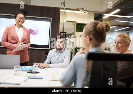 Geschäftsleute sitzen am Tisch und hören Geschäftsfrau während der Business-Ausbildung im Büro Stockfoto