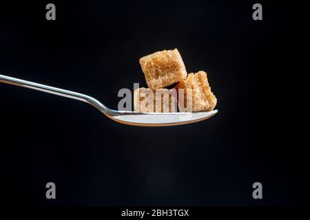 Löffel mit Würfel von braunem Demerara Zucker Stockfoto