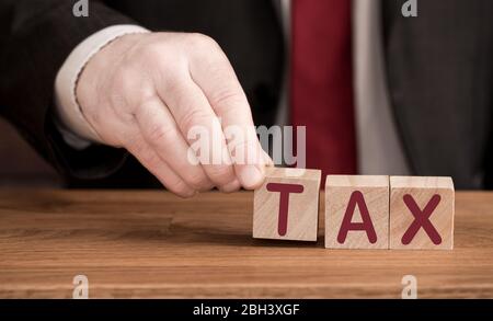 Ein Steuerkonzept für die Buchführung mit einem Buchhalter, Arbeitgeber oder Geschäftsmann und dem Wort STEUER aus Holzbriefblöcken Stockfoto