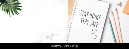 Worte bleiben zu Hause, bleiben Sie sicher in Notizbuch geschrieben, Konzept der Selbstquarantäne zu Hause als vorbeugende Virus Flat Lay Banner Stockfoto