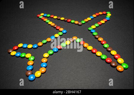M&M Süßigkeiten Stücke machen eine Flugzeug-Form auf schwarzem Hintergrund Stockfoto