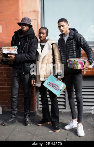 London, Großbritannien - 15 Januar, 2020, modische Menschen auf der Straße . Straßenstil. Drei stilvoll gekleidete junge Männer mit Schuhkartons in den Händen possin Stockfoto