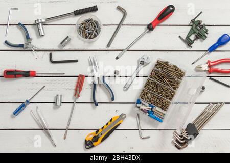 Die Tischlerwerkzeuge breiten sich auf einem hölzernen Tisch aus den weißen Brettern aus. Stockfoto