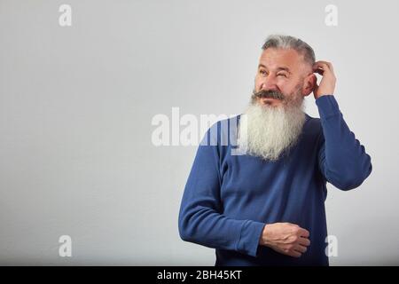 Porträt von nachdenklichen reifen grauhaarigen bärtigen Mann auf grauem Hintergrund, selektive Fokussierung Stockfoto