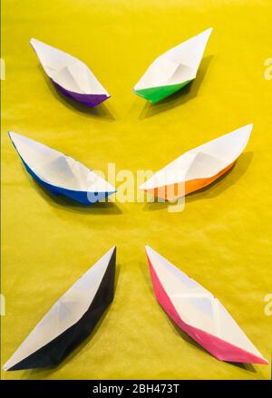 Bunte Aquarell bemalte Papierboote auf gelber Oberfläche symmetrisch angeordnet Stockfoto